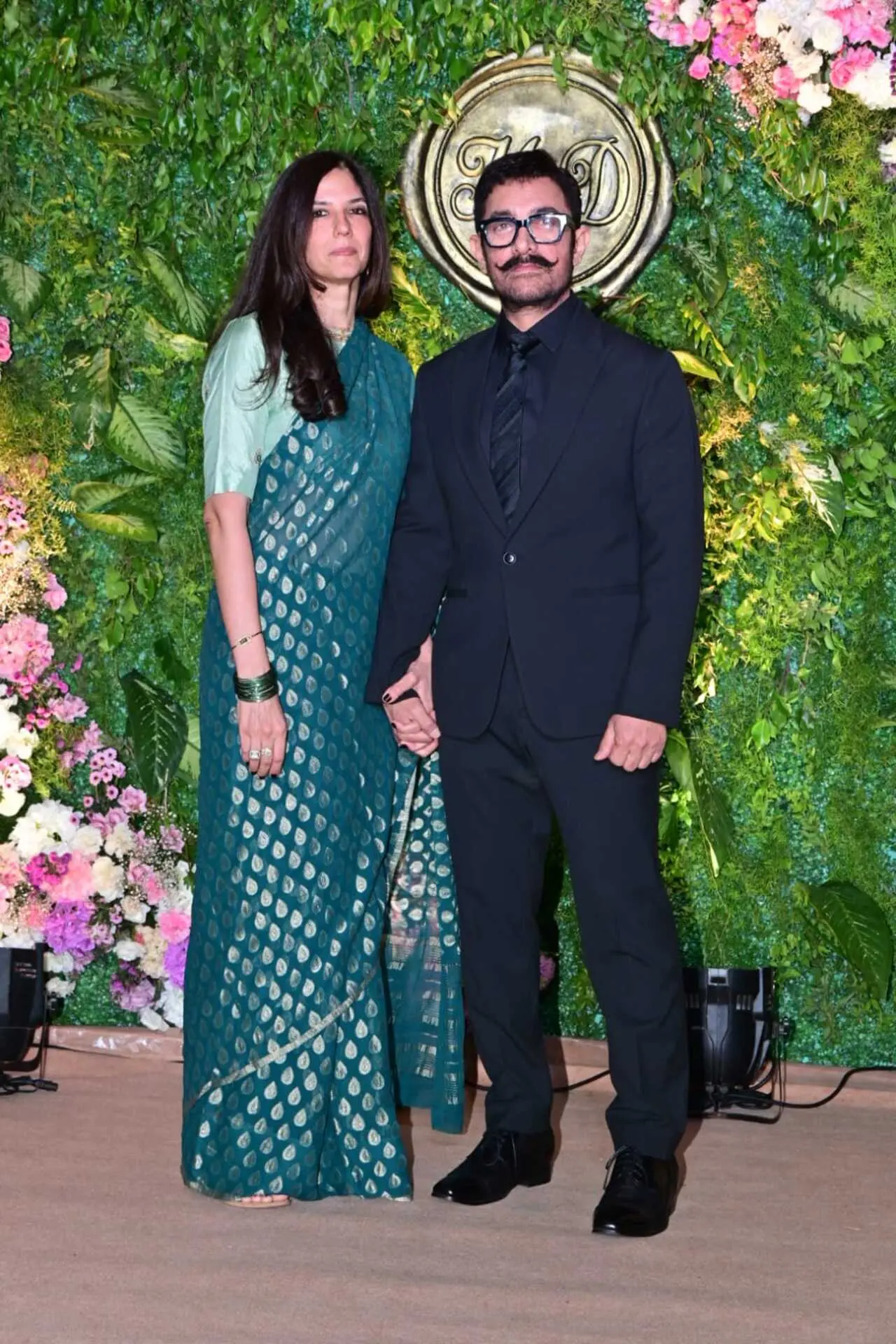 Aamir Khan attended the pre-wedding celebration with Gauri Spratt. The actor kept it sharp in a classic black suit paired with a black shirt and tie, while Gauri complemented him in an elegant green saree with gold motifs.